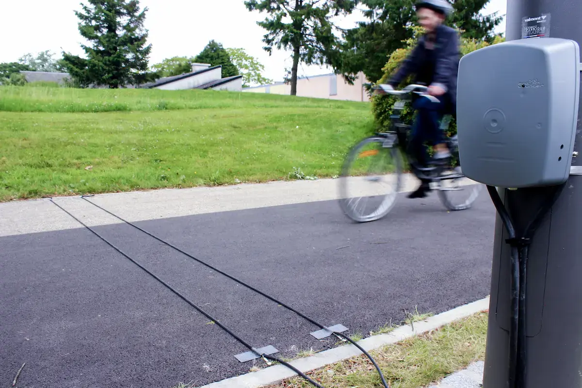 Eco-Counter MULTI inductive loop counter installed on a paved bike path with pneumatic tubes embedded in the surface for bicycle detection
